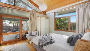 a bedroom with a bed and a chair and windows at Tea House - The Vintage in Pokolbin