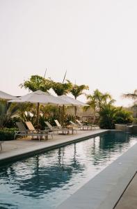 a swimming pool with tables and umbrellas and chairs at Maritime Apartment Sea View in Huatulco, 2 Rec in Bahías de Huatulco