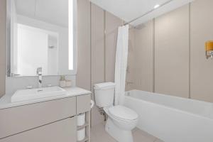 a white bathroom with a toilet and a sink at Prime 2BR Condo with Massive Patio & Parking in Toronto