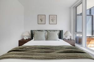 a white bedroom with a large bed with two lamps at Prime 2BR Condo with Massive Patio & Parking in Toronto