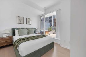 a bedroom with a large bed and a large window at Prime 2BR Condo with Massive Patio & Parking in Toronto