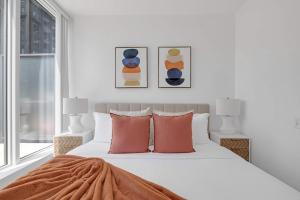 a white bedroom with a bed with orange pillows at Prime 2BR Condo with Massive Patio & Parking in Toronto +30 photos