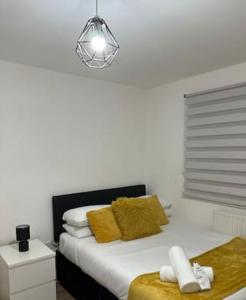a bedroom with a bed with yellow pillows and a light at Luxury Apartment in Milton Keynes with Netflix in Broughton