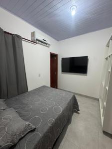 a bedroom with a bed and a flat screen tv at Flat Mobiliado no centro in Redenção