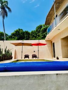 プエルト・エスコンディードにあるCasa Tachuのパラソル2本とテーブル付きのスイミングプール