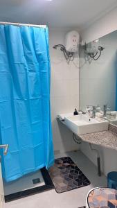 a bathroom with a blue shower curtain and a sink at Gerian's Suite in Luanda