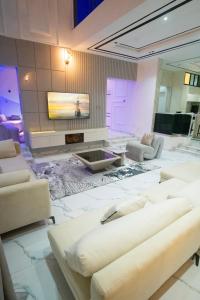 a living room with white furniture and a tv at Lily Luxury Home Shortlet Apartments 