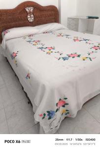 ein Bett mit einer weißen Decke mit Blumen darauf in der Unterkunft TS Transient House in Baguio City