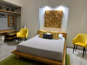 a bedroom with a bed and two yellow chairs at Acogedora suite con entrada independiente in Minatitlán