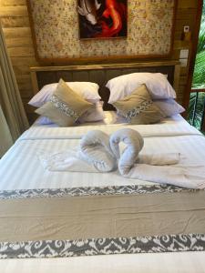 Dos toallas están hechas para parecer corazones en una cama en Infinity Villa and Resto, en Tembuku