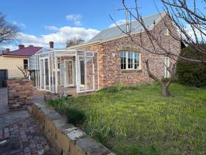 una casa in mattoni con porte e finestre bianche di The Podium Accommodation - Oatlands, Tasmania a Oatlands