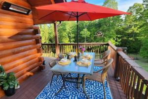 a table with a red umbrella on a deck at Solar powered log cabin with mountain views, 3acres in Lake Lure