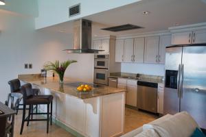 a kitchen with white cabinets and a island with fruit on the counter at The Cliff View in Cupecoy