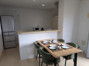 a kitchen with a wooden table and green chairs at Yomitan 4LDK house in Yomitan