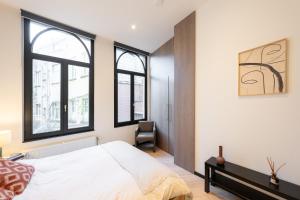 een slaapkamer met een bed en twee ramen bij A Marbled Touched Haven in Antwerpen