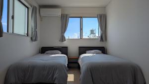 two beds in a room with a window at Yomitan 4LDK house in Yomitan
