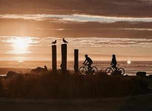 un gruppo di persone che cavalca biciclette sulla spiaggia al tramonto di The Lilly Pad - Hokitika a Ruatapu Altre 32 foto