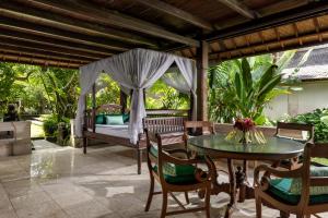 un patio con cama, mesa y sillas en Honeymoon Guesthouse, en Ubud