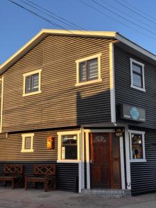 Un edificio de madera con un banco delante. en Hostal B&B Coastal Natales, en Puerto Natales
