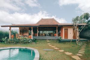 a house with a swimming pool in front of it at Tebola Joglo Villas in Sidemen