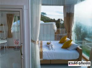 een slaapkamer met een bed en een groot raam bij ชาเลต์ ภูทับเบิก in Ban Maeo Thap Boek +21 foto's