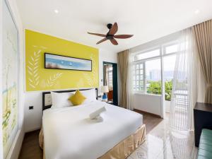 a bedroom with a large white bed with a yellow wall at Sujet Beach Hotel and Apartment Danang by Haviland in Da Nang
