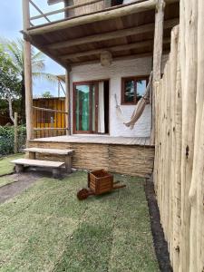 een houten huis met een hangmat en een hek bij Há Mar Chalés Corumbau in Prado