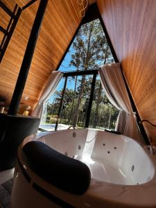 a bath tub in a room with a large window at Chalé Araucárias Cambará do Sul in Cambará +43 photos