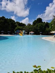 a large pool of blue water with a playground at Apartamento na Barra de São Miguel in Barra de São Miguel
