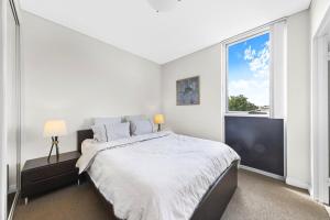 シドニーにある2BR APT Ideal for Families or Business Staysの大きなベッドと窓のある白い寝室