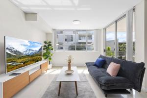 シドニーにある2BR APT Ideal for Families or Business Staysのソファとテレビのあるリビングルーム
