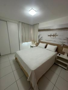 a bedroom with a bed and a painting of boats at Apartamento na Barra de São Miguel in Barra de São Miguel