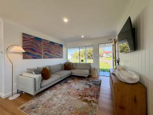 a living room with a couch and a tv at Cooinda on the Green - Your Happy Place! Golf Course Retreat with Kangaroo Views in Sanctuary Point