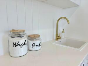 two jars sitting on a kitchen counter next to a sink at Cooinda on the Green - Your Happy Place! Golf Course Retreat with Kangaroo Views in Sanctuary Point +35 photos
