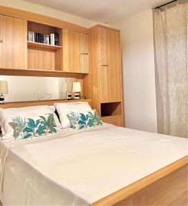 a bedroom with a large white bed with wooden cabinets at Le Nid du rocher in Le Diamant