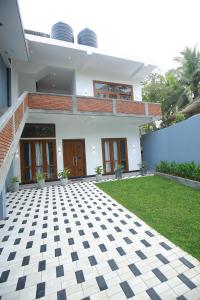 a white house with a black and white checkered floor at Danu Surf House Hiriketiya in Dickwella