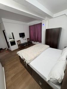 a bedroom with a large white bed in a room at Hotel Kunzin in Tawang