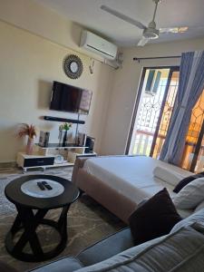 a bedroom with a bed and a couch and a tv at Homely studio Apartment 2 in Mombasa
