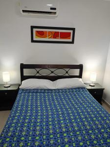 una camera da letto con un letto con copriletto blu e 2 lampade di Valdy hause 202 a Gaira