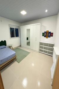 Schlafzimmer mit einem Bett und weißen Wänden in der Unterkunft Casa para temporada em Garopaba in Garopaba