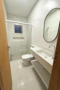 ein weißes Bad mit einem WC und einem Spiegel in der Unterkunft Casa para temporada em Garopaba in Garopaba