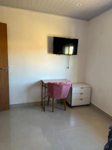 Zimmer mit einem Tisch und einem TV an der Wand in der Unterkunft Casa para temporada em Garopaba in Garopaba + 1 Foto