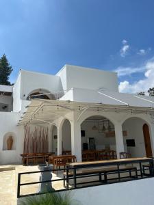 a white building with wooden tables and chairs at Villa Ramos in Tangkubanperahu
