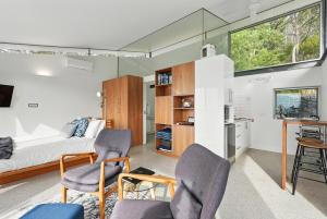 a bedroom with a bed and two chairs and a table at Eaglehawk Pavilions in Eaglehawk Neck