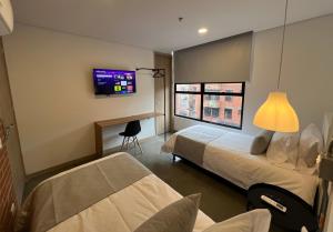 a bedroom with a bed and a tv on the wall at Akela30 Hotel in Medellín