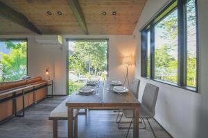 una sala da pranzo con tavolo in legno e alcune finestre di Greyton A - Brand new chic bright spacious 2BR a Wada