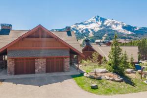 a house with a garage with a mountain in the background at Cozy Condo | Hot Tub Views | Steps to Ski Shuttle in Big Sky Mountain Village
