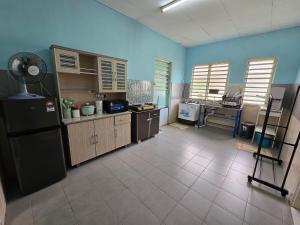 a large kitchen with a refrigerator and a fan at Irah Homestay in Kuantan