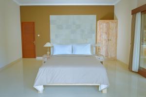 una camera da letto con un grande letto bianco con cuscini blu di Villa Padma Ubud ad Ubud