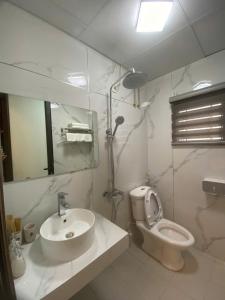 Un baño con lavabo, inodoro y espejo. en Hạ Long Xanh, en Hanói